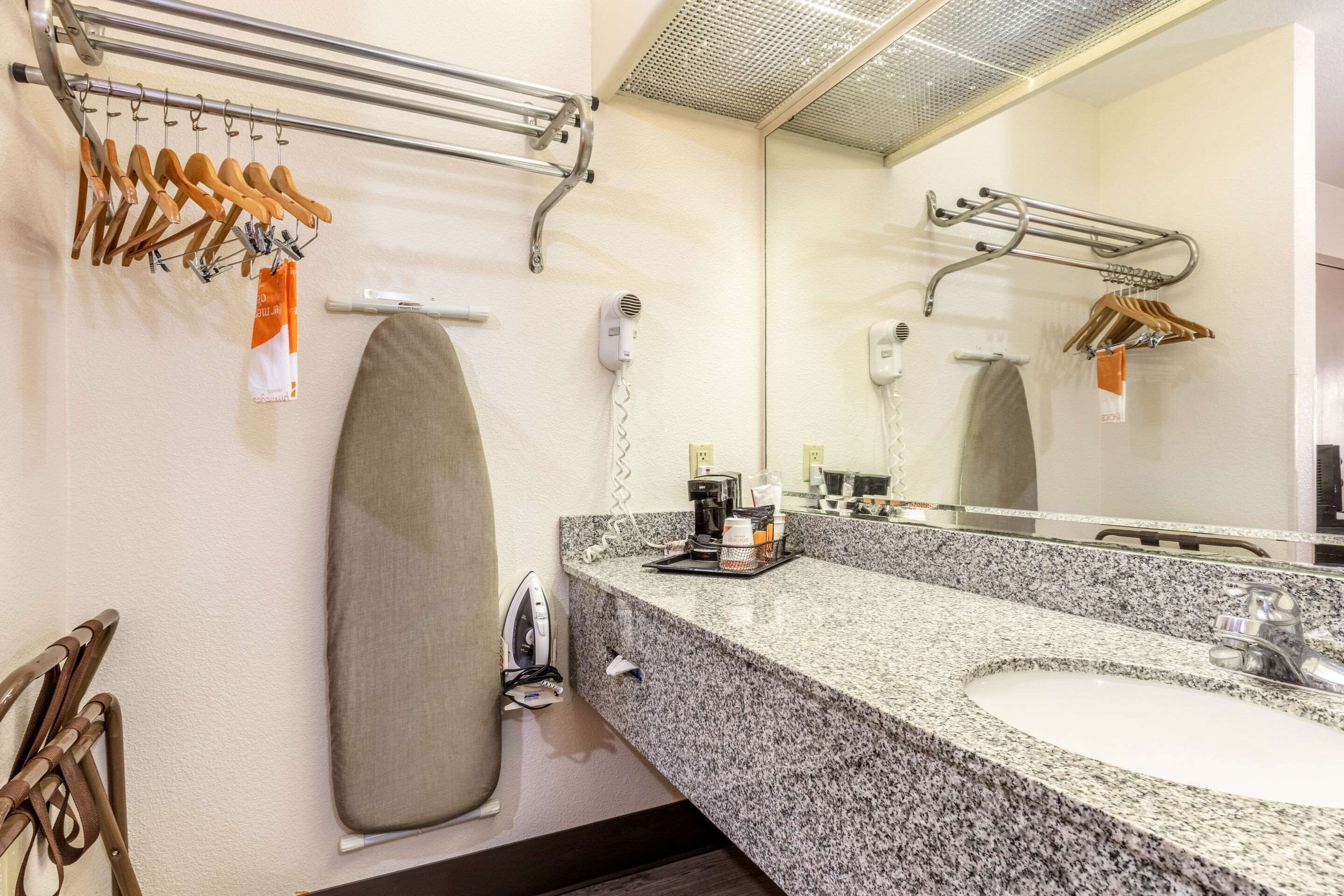 A bathroom with a granite countertop, a sink, a mirror, a towel rack, and a hairdryer.