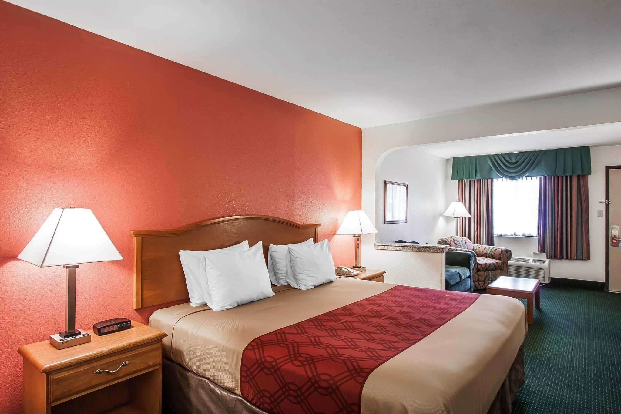 Une chambre d’hôtel avec un grand lit, deux tables de chevet avec des lampes, un bureau et une chaise.