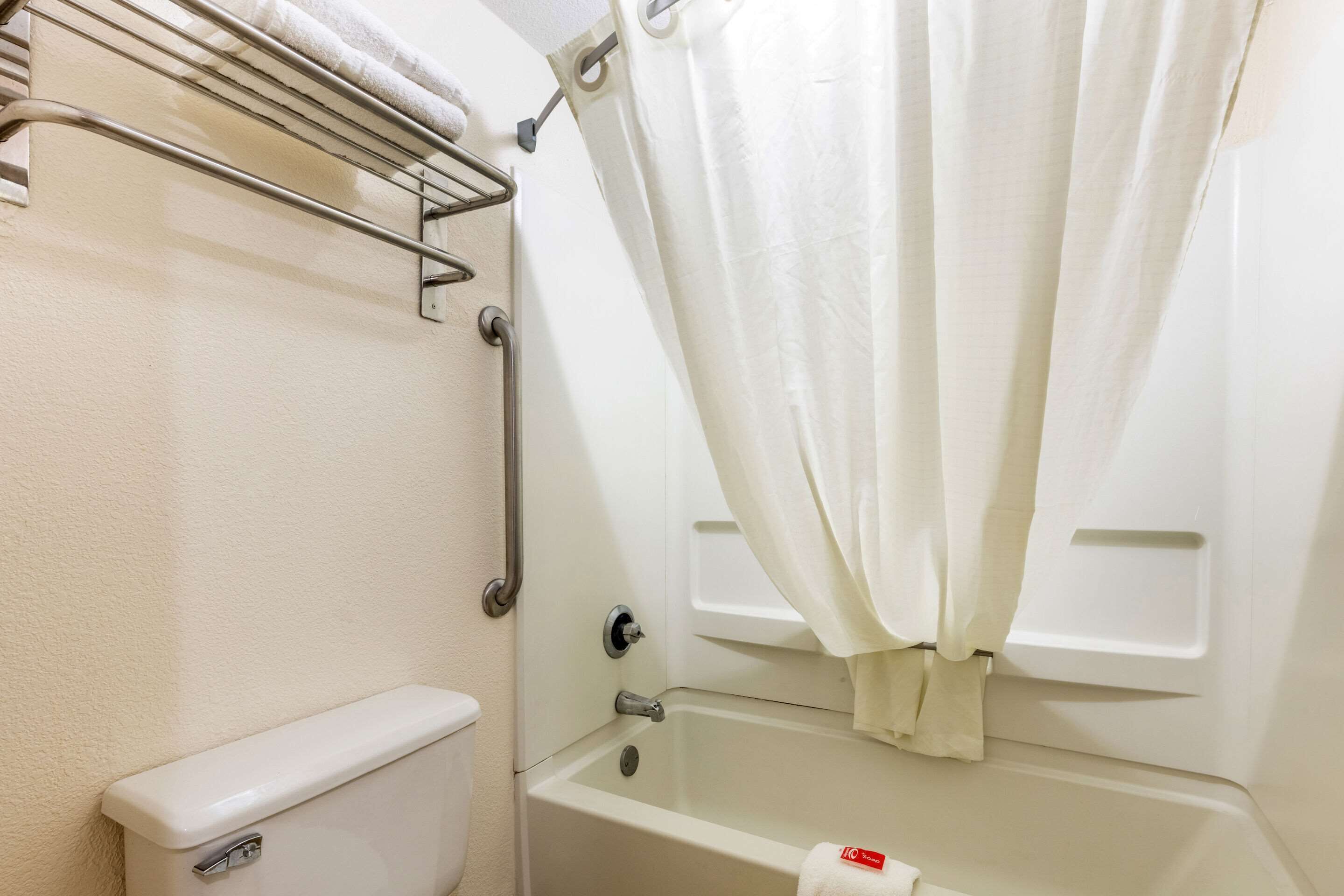 Une salle de bain équipée de toilettes, d’une baignoire, d’un rideau de douche et d’un porte-serviettes.