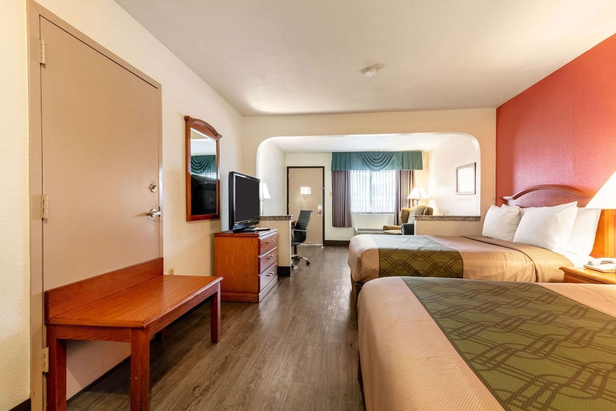 A hotel room with a bed, a desk, a television, a chair, and a window with curtains.