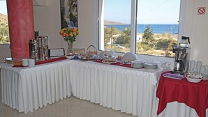 A buffet table with white tablecloths and red accents, set against a backdrop of a scenic coastal view. - Hotel Sea Breeze (Sitia)