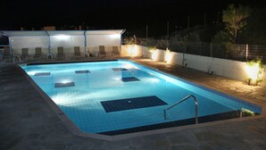 A swimming pool with a tiled deck and a covered seating area. - Hotel Sea Breeze (Sitia)