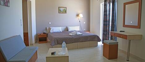 A bedroom with a bed, a bedside table, a desk, a chair, and a bedside lamp.
