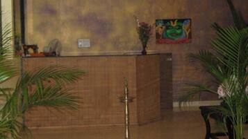 A reception area with a wooden reception desk, a brass oil lamp, and a painting on the wall.