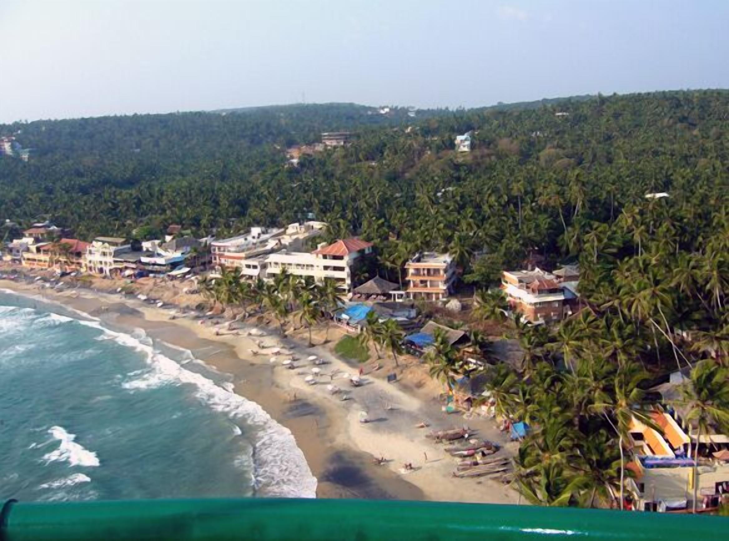 Una zona costera con edificios, una playa y palmeras.