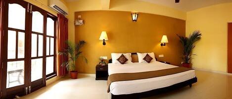 Una habitación de hotel con una cama grande, dos mesitas de noche, un televisor y una ventana con cortinas.