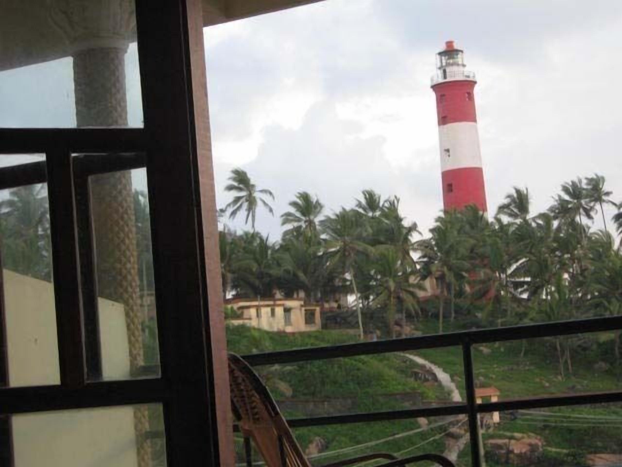 Vue d’un phare rouge et blanc, prise de l’intérieur d’un bâtiment doté de grandes fenêtres.