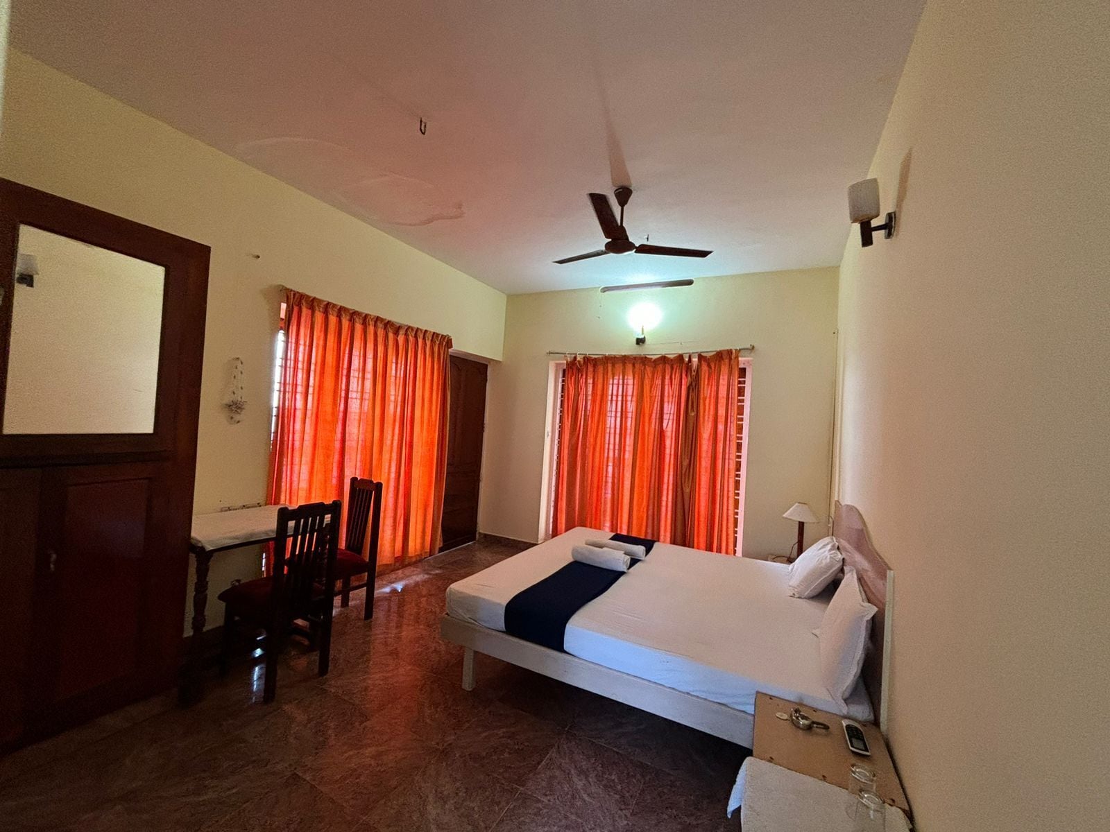 A bedroom with a bed, a desk, a chair, and a ceiling fan.
