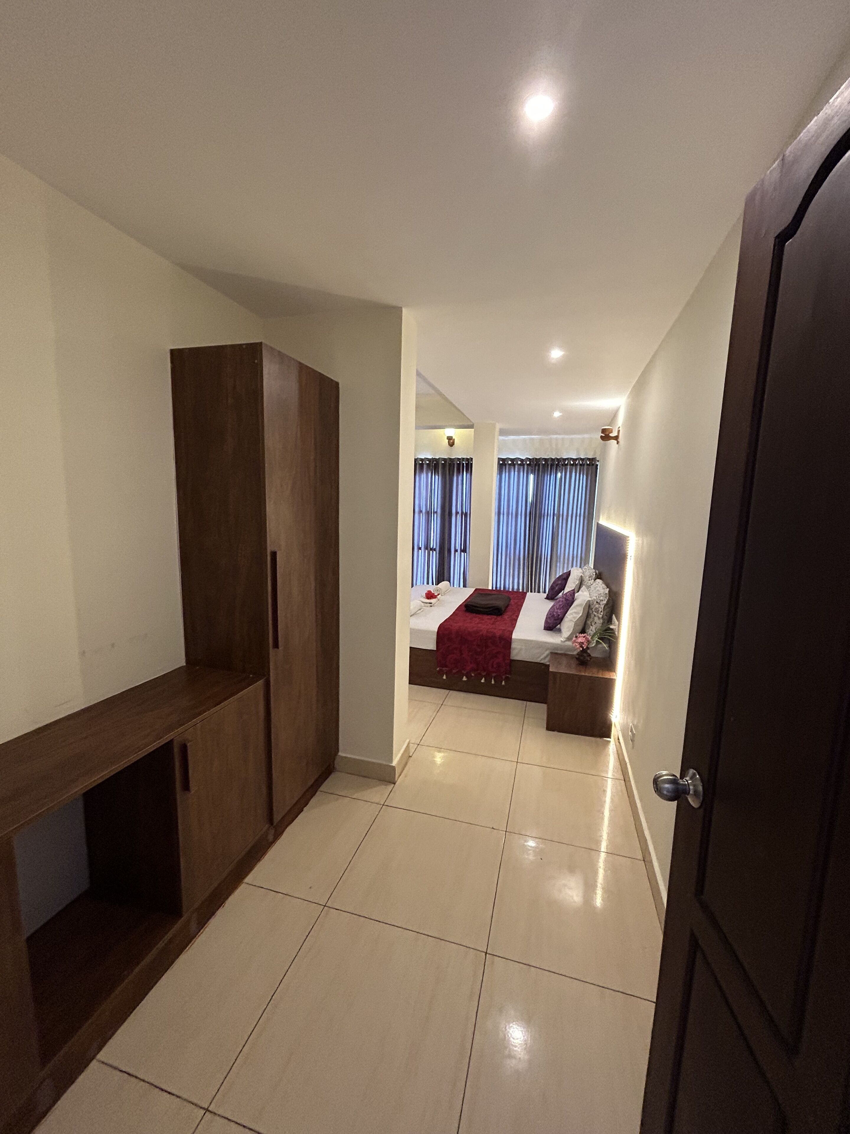 A hotel room with a bed, bedside tables, a wardrobe, and a bathroom visible through an open door.