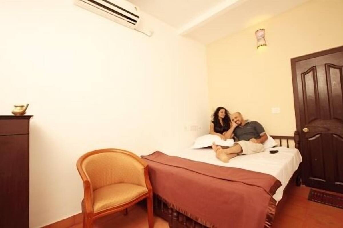 A small, cozy room with a bed, a chair, and a wooden door.