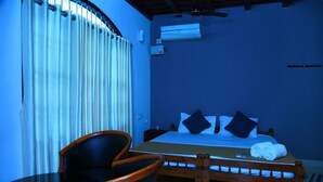 Una habitación de hotel con cama, una silla, una mesa y una ventana con cortinas.
