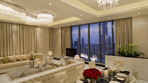 A luxurious living room with a city view, a dining area, and a large chandelier. - DAMAC Maison Mall Street (Dubai)