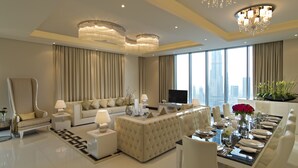 A modern living room with a sofa, a dining table set for six, and a large window with a city view. - DAMAC Maison Mall Street (Dubai)