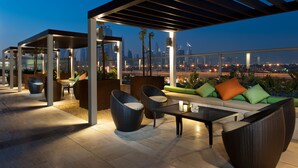 An outdoor lounge area with seating and a city view at dusk. - DAMAC Maison Mall Street (Dubai)