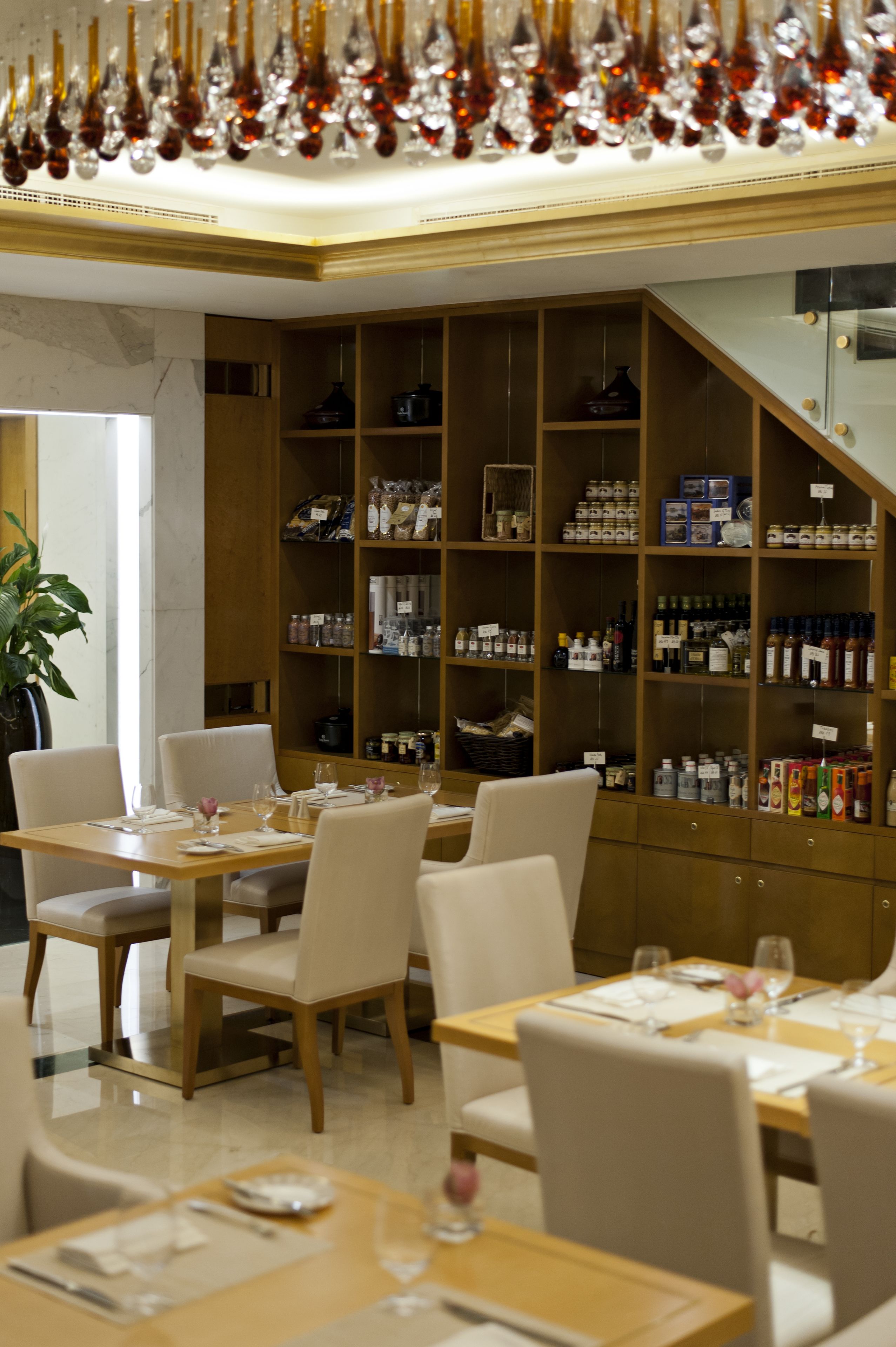 En restaurant med flere spiseborde og stole, et stort udvalg af vin og spiritus, og en potteplante.