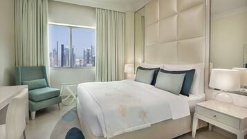 A hotel room with a large bed, a chair, a nightstand, and a view of a city skyline.
