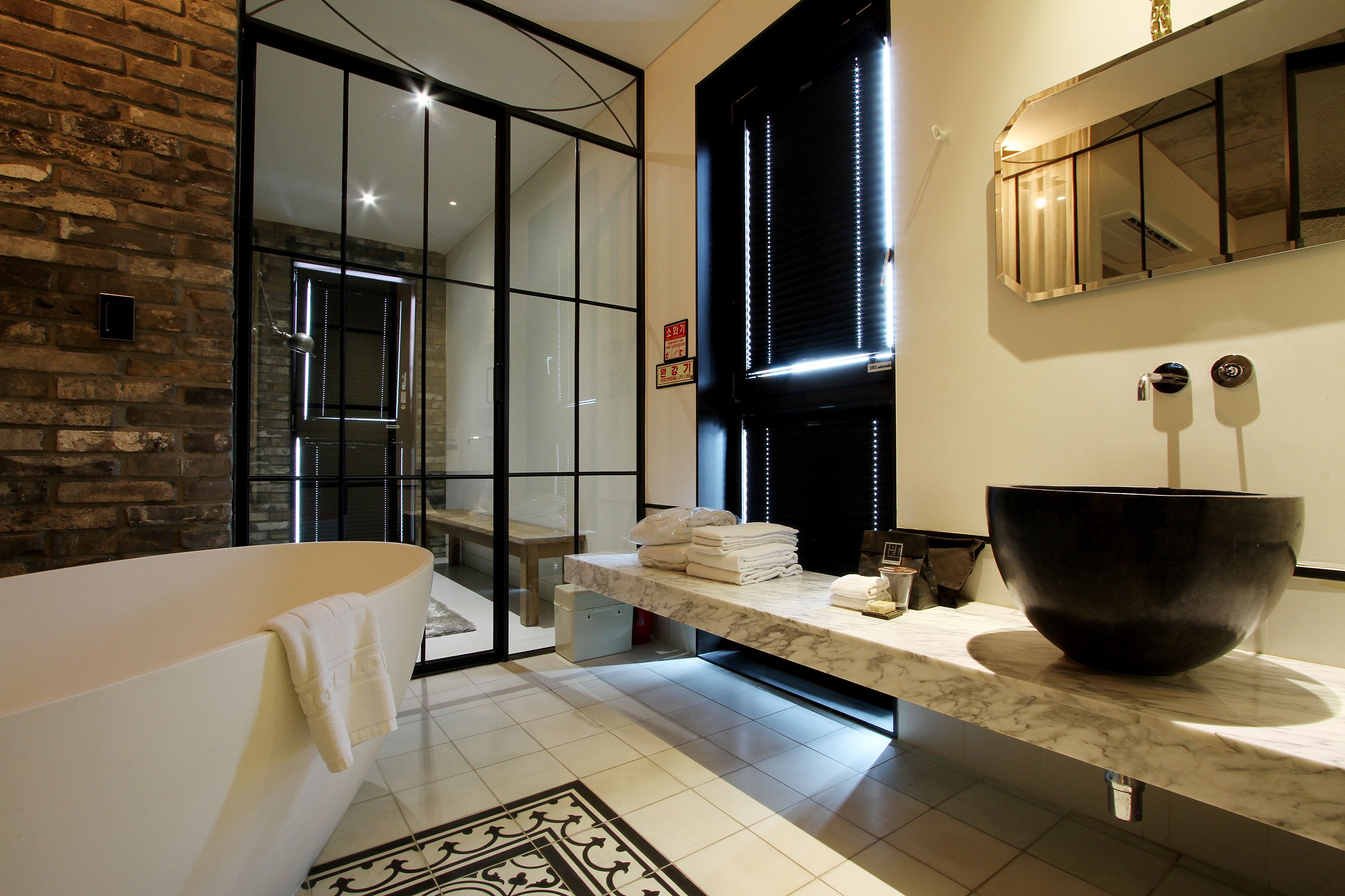 A modern bathroom with a large bathtub, a marble countertop, a large black basin, and a glass shower enclosure.