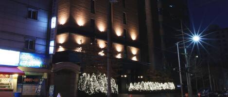 A multi-story hotel with illuminated windows and a sign indicating it is a hotel.