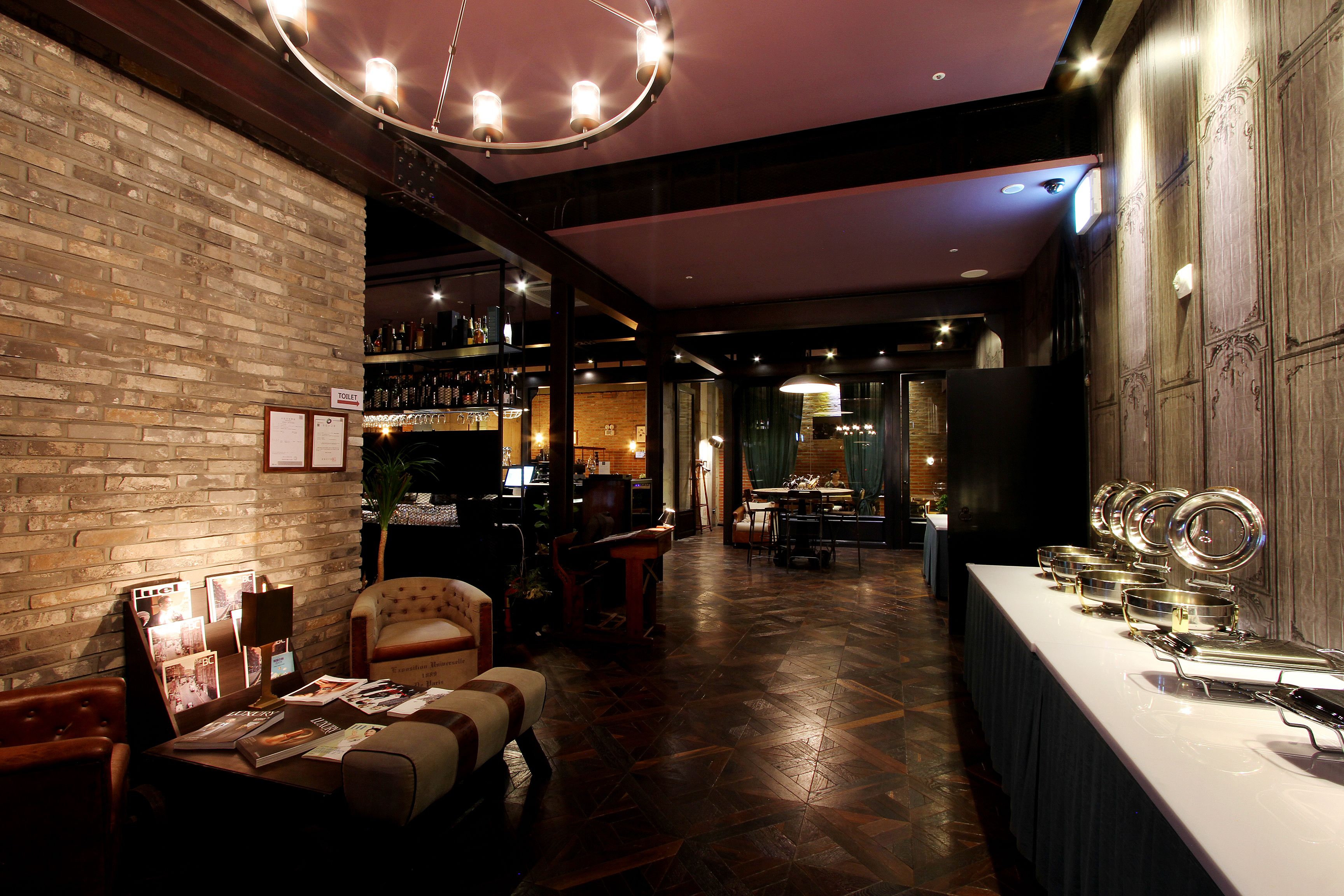 A bar area with a brick wall, wooden flooring, and a long counter with glasses.