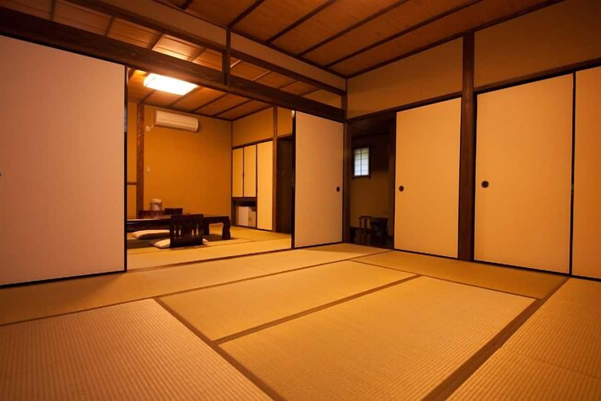 Una habitación tradicional con tatami, puertas correderas, una pequeña mesa y un televisor.