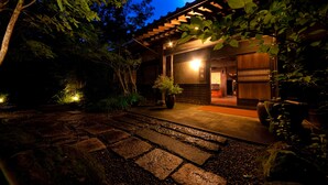 A traditional Japanese-style building with a wooden exterior and a stone pathway leading to the entrance. - Yufuin Gettouan (Yufu)