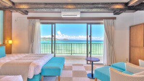 A hotel room with a large bed, a small table, and a view of the ocean.