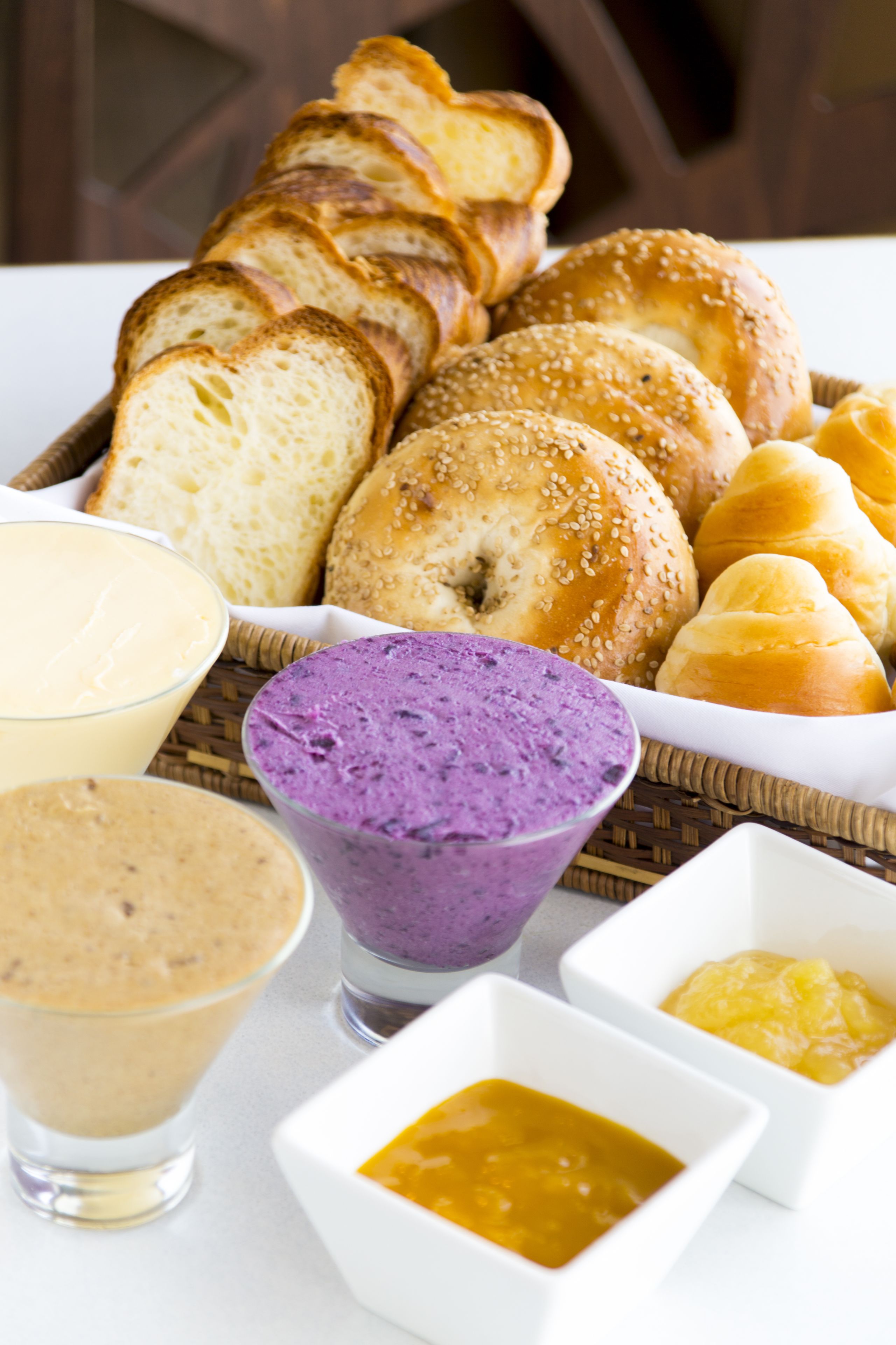 A table with various food items including bread, a purple dessert, and two types of sauces.