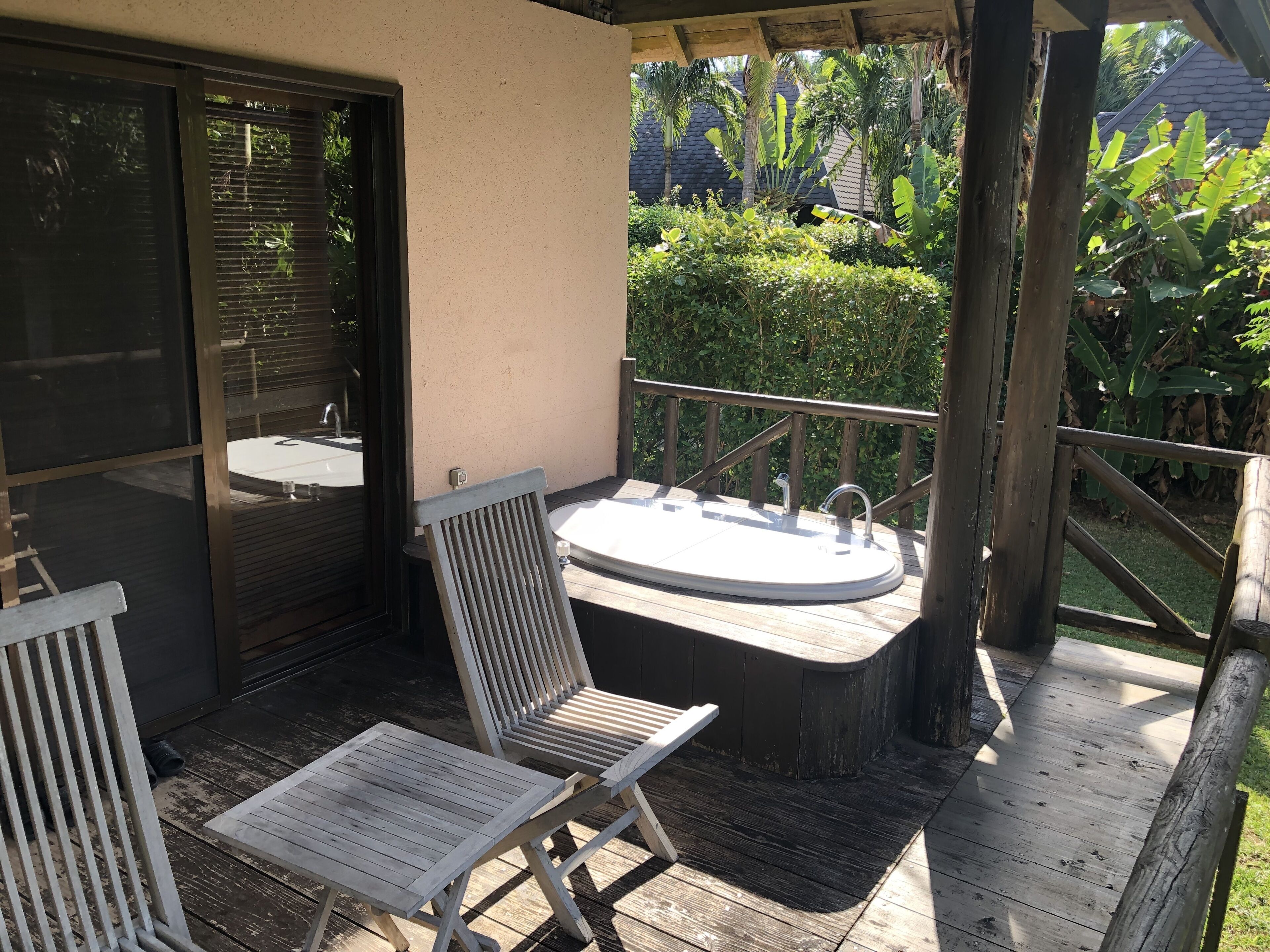 Une terrasse en bois avec un jacuzzi, une chaise et une petite table.