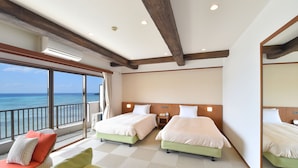 A hotel room with two beds, a balcony with a view of the ocean, and a large mirror.