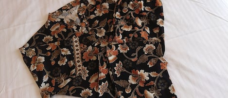 Una cama con sábana blanca y una prenda floral negra sobre ella.