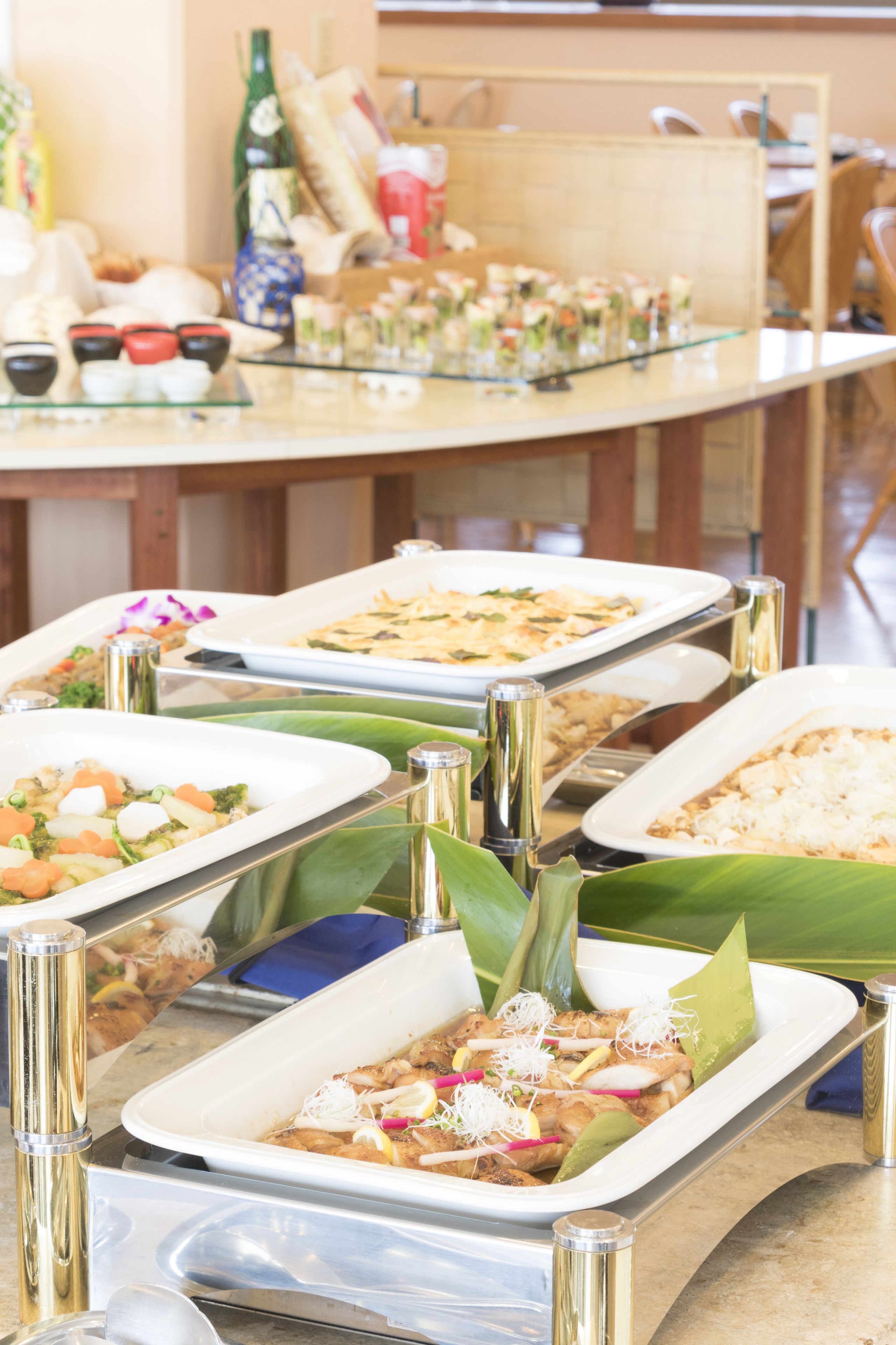 A buffet with various dishes, including seafood and salads, arranged on a glass table with metal stands.