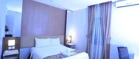 A hotel room with a large bed, two bedside tables, a nightstand, a desk, and a chair.