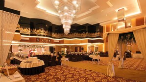 Une salle de banquet avec des tables rondes, un grand lustre et des rangées de sièges en gradin.