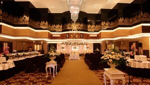 Une salle de banquet avec une allée centrale, des tables de chaque côté et un lustre.