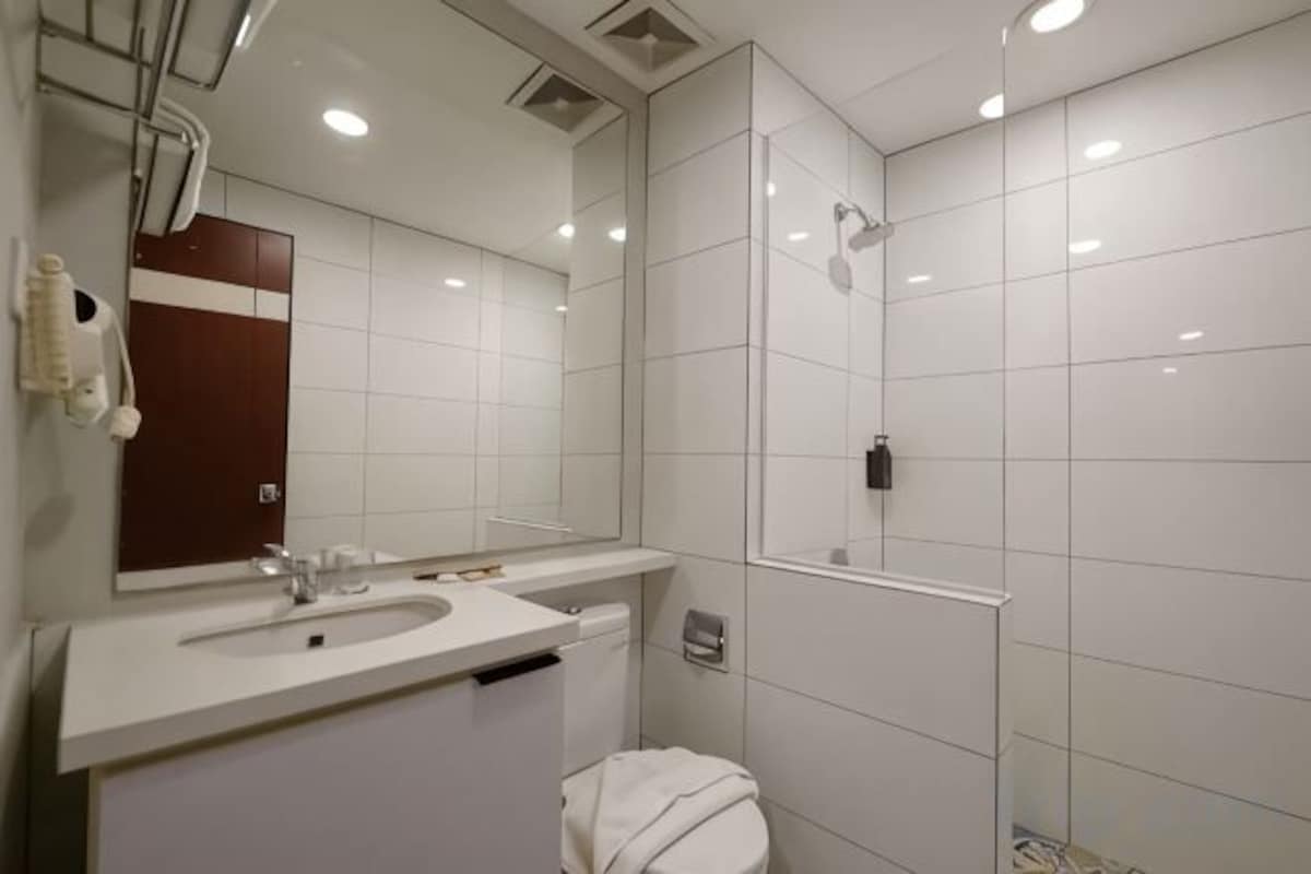 Un baño moderno con lavamanos, espejo y ducha blancos.