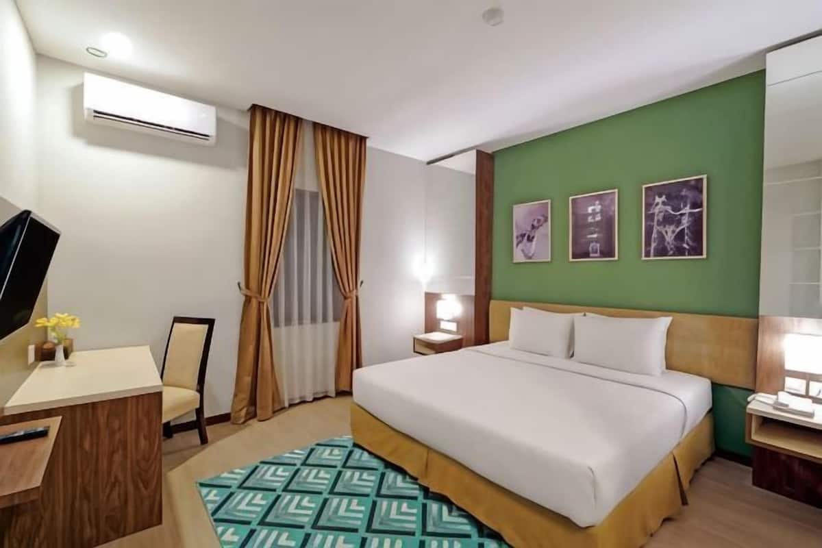 Ein Hotelzimmer mit Bett, Schreibtisch, Stuhl und Fernseher.