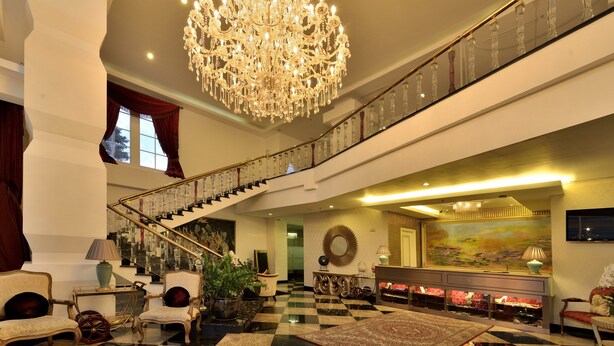 A grand lobby with a large chandelier, a checkered floor, a staircase, and a large painting on the wall. - Amaroossa Royal Bogor (Bogor)