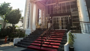 A building entrance with a glass canopy, red carpeted steps, and a black railing. - Amaroossa Royal Bogor (Bogor)