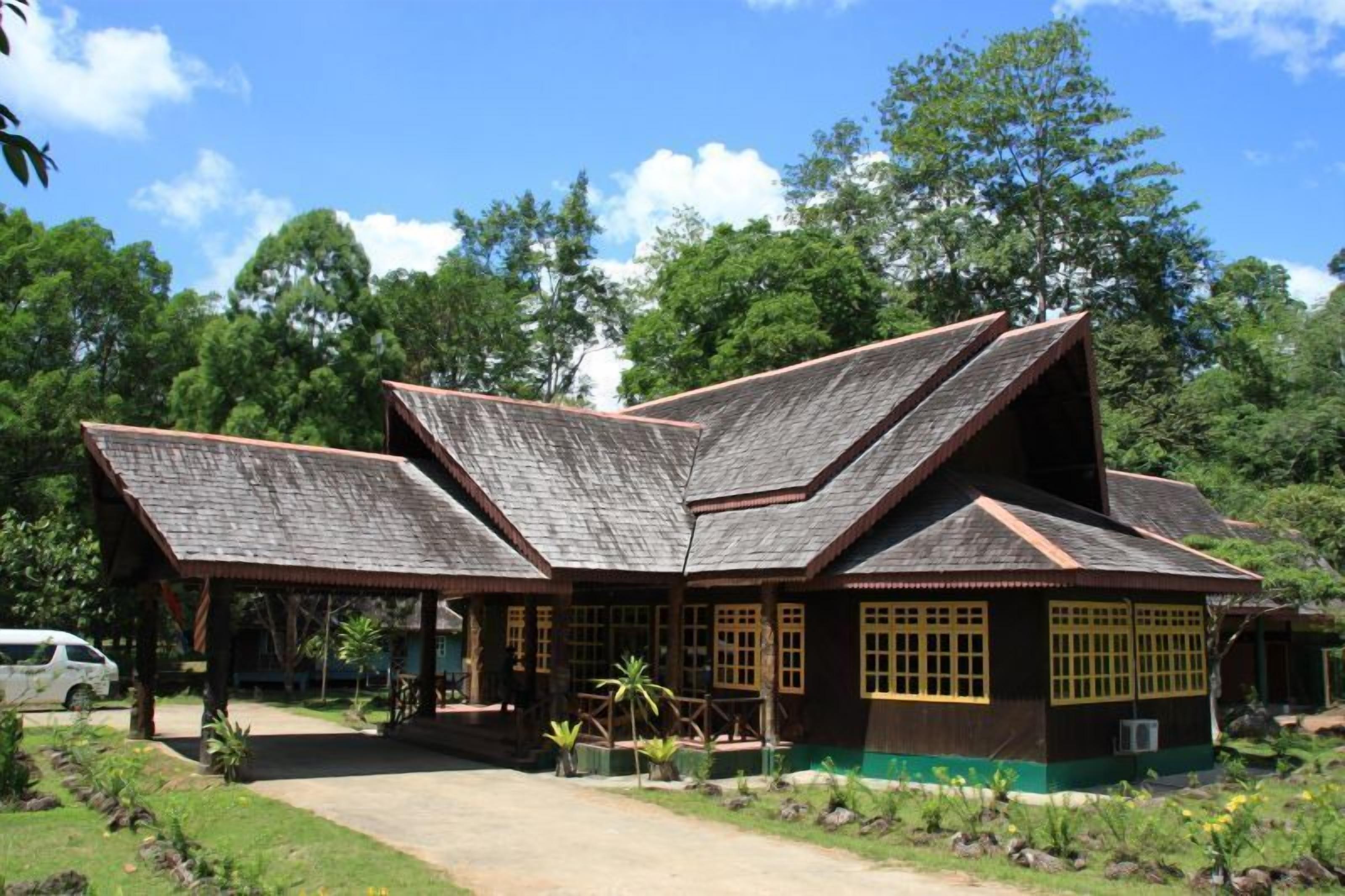Une maison traditionnelle en bois, dotée d’un toit à pente et entourée d’une végétation luxuriante.