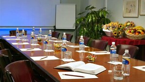 A conference room with a long table, chairs, water bottles, a projector screen, a whiteboard, and a plant. - Tabin Wildlife Resort (Lahad Datu)