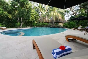 Una piscina al aire libre, sombrillas, sillones reclinables de piscina