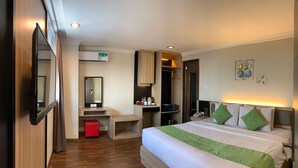 Una habitación de hotel con cama, mesita de noche, espejo, armario y un taburete rojo.