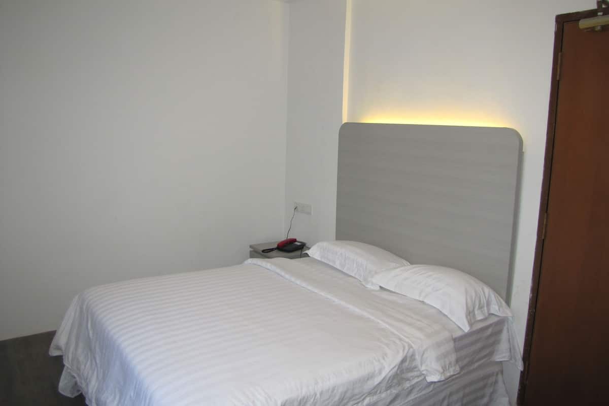 A small, simple bedroom with a bed, a nightstand, and a bedside table.