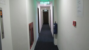 A narrow hallway with a carpeted floor, a fire extinguisher mounted on the wall, and a sign indicating the direction to the kitchen. - Park Hotel (Kota Kinabalu)
