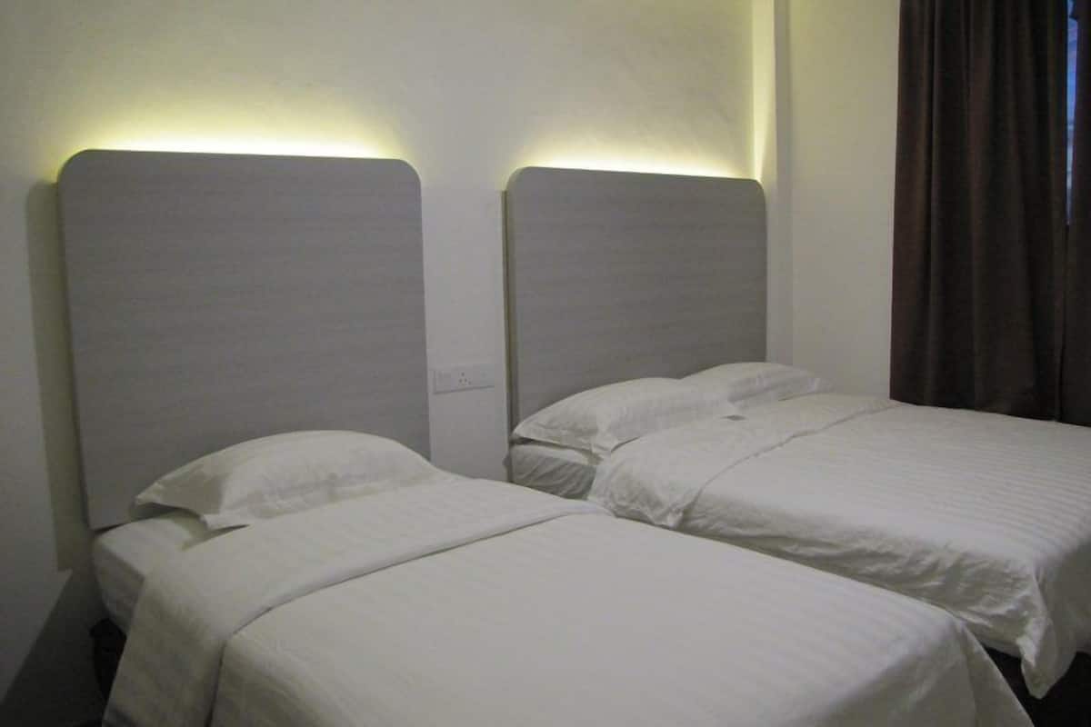 A hotel room with two single beds, each with a headboard and a white bedspread.