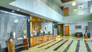 A hotel reception area with a marble wall, reception desk, seating, and a staircase. - Oak Tree Emerald Hotel & Conventions Semarang (Semarang)