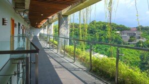 A covered walkway with glass railings overlooking a lush green landscape. - Oak Tree Emerald Hotel & Conventions Semarang (Semarang)