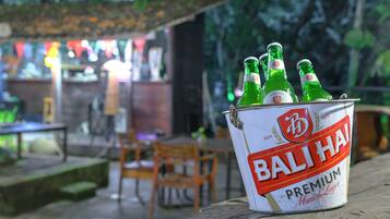 A can of Bali Hai beer on a wooden surface with a blurred background of an outdoor seating area.
