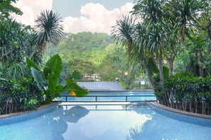 A swimming pool surrounded by lush tropical vegetation and a view of a forested hillside. - Oak Tree Emerald Hotel & Conventions Semarang (Semarang)