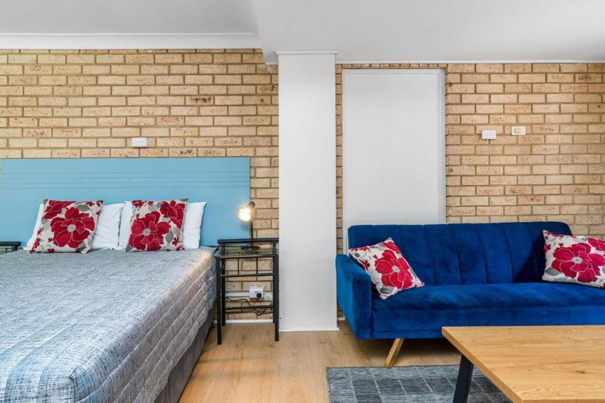 A room with a bed, a blue sofa, and a small table.